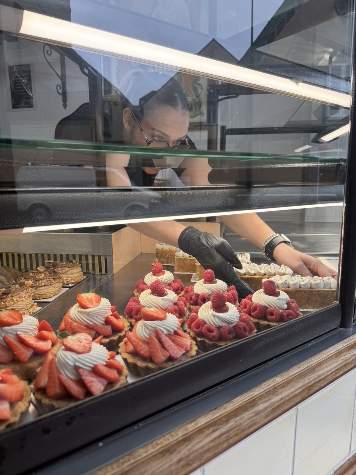 Artisan de l'Atelier Lefebvre disposant les pâtisseries en vitrine